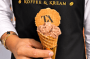 A server wearing a black koffee and kream apron holding a cone of bueno gelato
