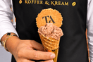A server wearing a black koffee and kream apron holding a cone of bueno gelato